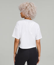 Load image into Gallery viewer, Back of a woman wearing a white t-shirt and black shorts from lululemon