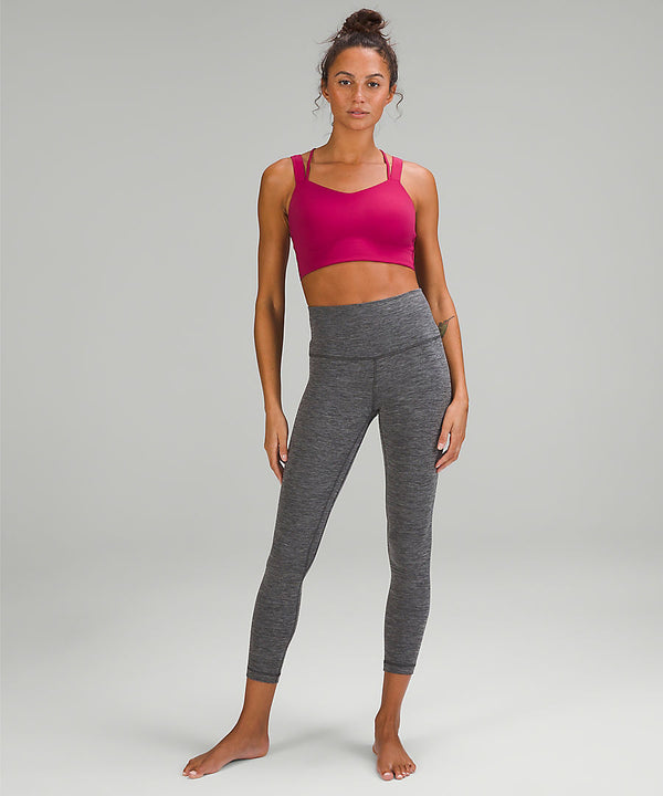 woman wearing a pink sports bra and grey yoga leggings from lululemon