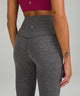 Close up of the back of a woman wearing a pink top and grey yoga leggings from lululemon