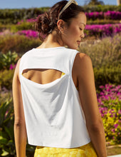 Load image into Gallery viewer, Back of a woman wearing a white tank top with yellow pants in front of a field of flowers. 
