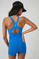 Woman wearing a blue runsie from free people and a black hat. 