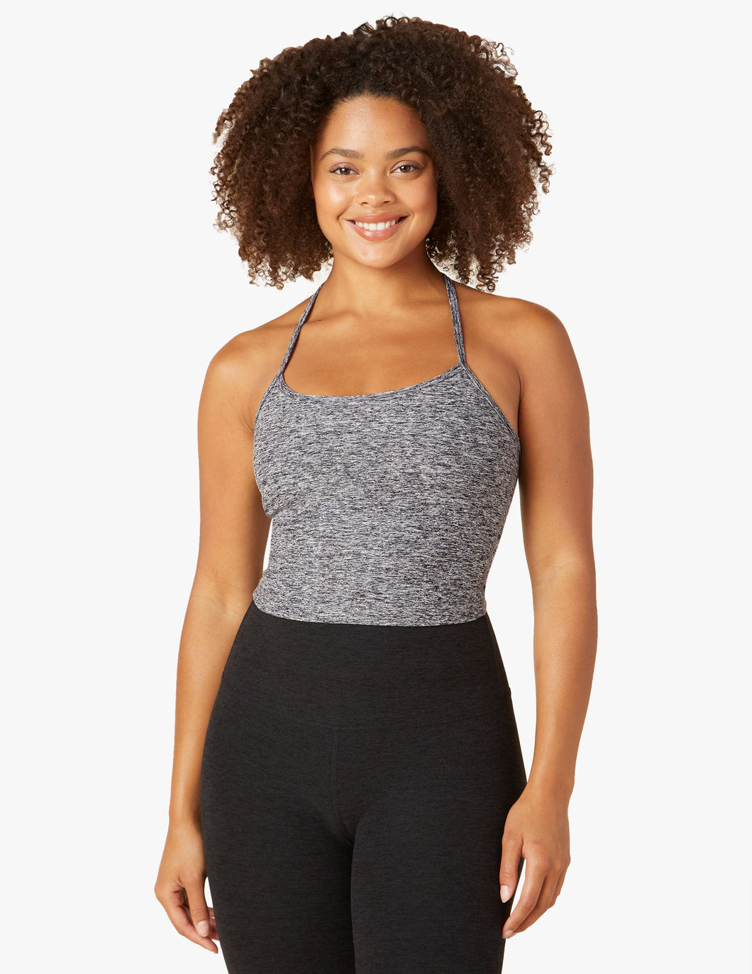 Woman wearing grey tank top and black yoga leggings from Beyond yoga. 