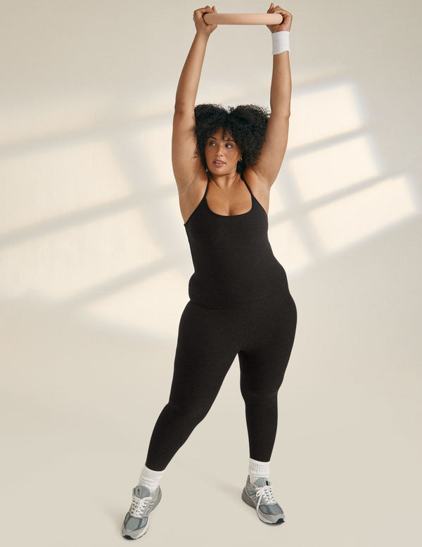 Model wearing black athletic jumpsuit with adjustable straps