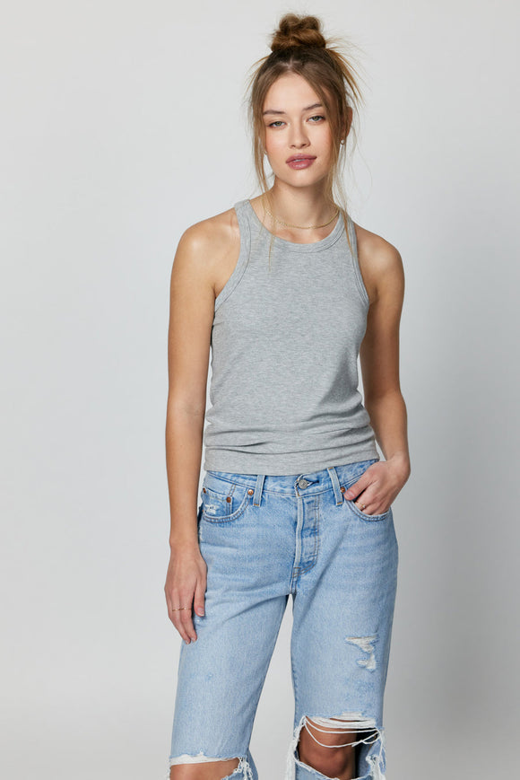Woman wearing a grey tank top and blue jeans.