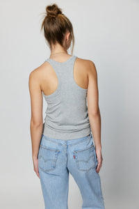 back of a woman wearing a grey tank top and blue jeans. 