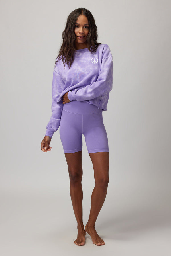 Woman wearing a purple and white tie dye sweater with purple shorts