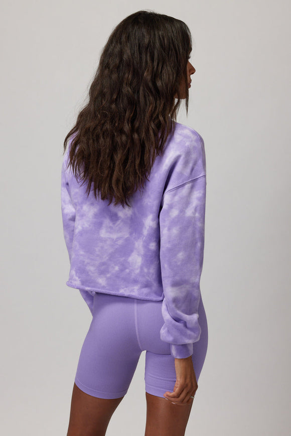 back of a Woman wearing a purple and white tie dye sweater with purple shorts
