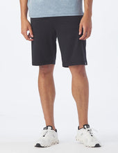Load image into Gallery viewer, Man wearing black shorts from Glyder and white sneakers.