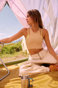 Woman in a tent wearing a tan and yellow tank top with khaki pants