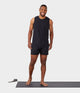 black male model standing on yoga mat wearing black tank and black athletic shorts