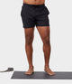 black male model standing on yoga mat wearing black athletic shorts