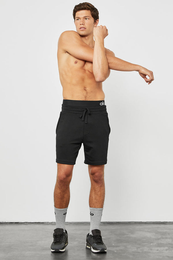 male model stretching wearing black athletic shorts 
