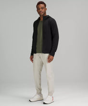 Load image into Gallery viewer, Male model wearing full zip black hoodie with a green shirt and cream colored joggers