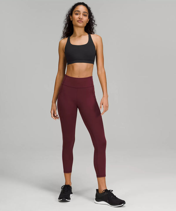 Female model wearing black sports bra and maroon leggings