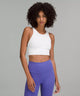 Black female model wearing white lululemon sports bra and purple leggings