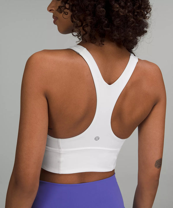 Black female model wearing white lululemon sports bra and purple leggings