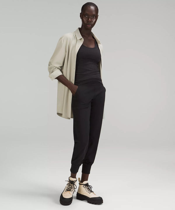 Female model wearing black joggers, black tank, cream boots, and cream shirt