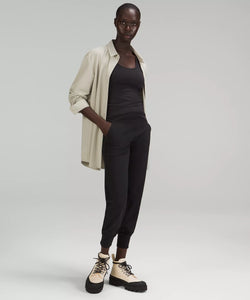 Female model wearing black joggers, black tank, cream boots, and cream shirt