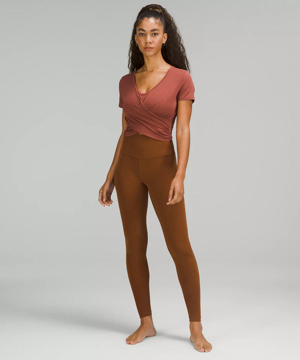Female model wearing brown leggings and a pink shirt