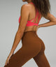 Female model wearing brown leggings and bright pink sports bra
