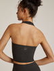 Back of Woman wearing Beyond Yoga Darkest Night halter top and darkest night yoga leggings. 