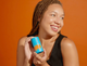 Female model smiling holding Heavy Does It Hydrator lotion from Goodspread