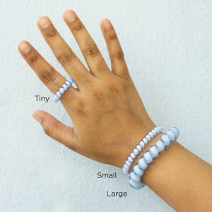 Hand with the three sizes of hair tie around wrist/finger to give scale for sizing