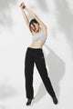 Female model wearing loose black sweatpants and stretching