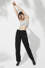 Load image into Gallery viewer, Female model wearing loose black sweatpants and stretching