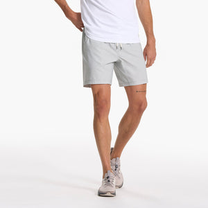 man wearing a white tshirt with vuori shorts and light grey sneakers