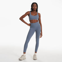 Load image into Gallery viewer, woman wearing a blue sports bra with blue yoga leggings and white sneakers. 
