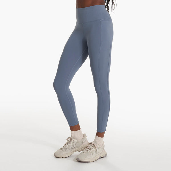 side view of a woman wearing blue yoga leggings and white sneakers