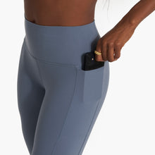 Load image into Gallery viewer, close up of a woman putting a phone in the pocket of her blue yoga leggings