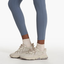 Load image into Gallery viewer, close up of a woman&#39;s feet wearing white sneakers, white socks and blue yoga leggings