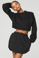 Black female model wearing black Alo Yoga pullover coverup