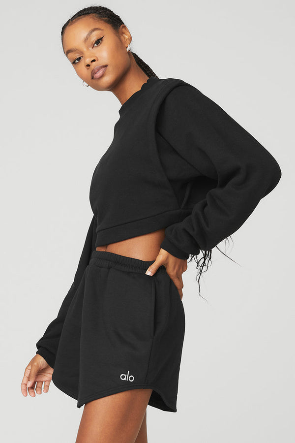 Black female model wearing black Alo Yoga pullover coverup