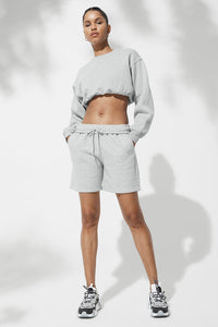 Female model wearing loose gray shorts  and matching crop hoodie from Alo Yoga