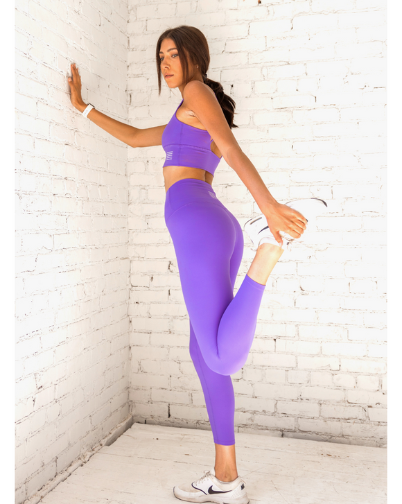 Female model wearing bright purple leggings from kosha fit