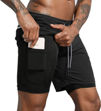 Load image into Gallery viewer, black male model pulling a phone out of his black athletic shorts