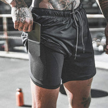 Load image into Gallery viewer, black male model with tattoos is pulling a phone out of his black athletic shorts
